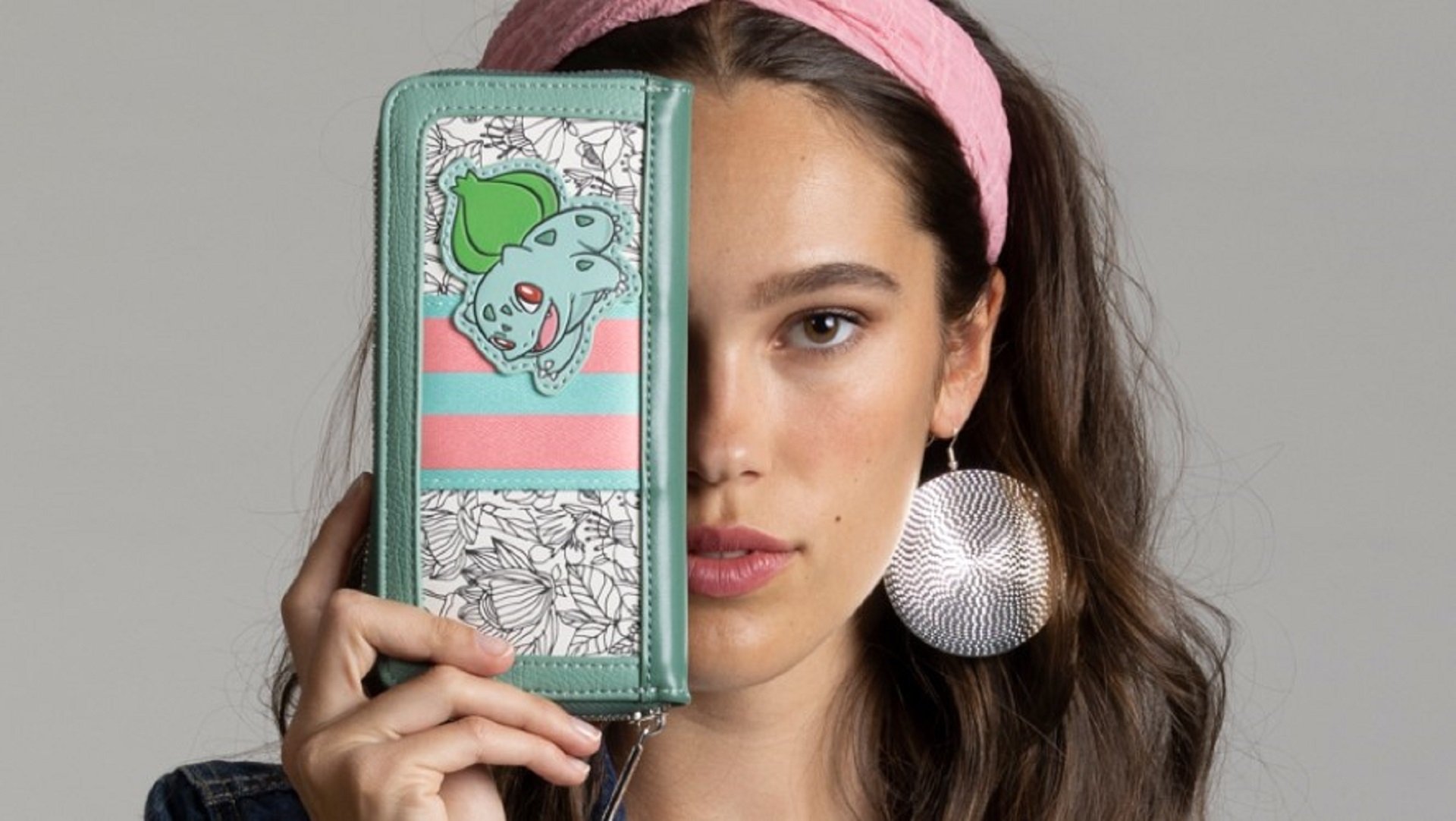 A model holds up a Danielle Nicole Pokémon wallet featuring Bulbasaur.