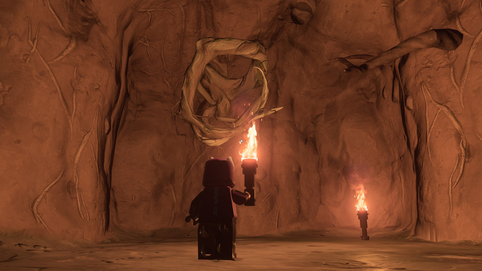 Fortnite player holding a torch, looking at knotroot wood growing out of a stone wall.