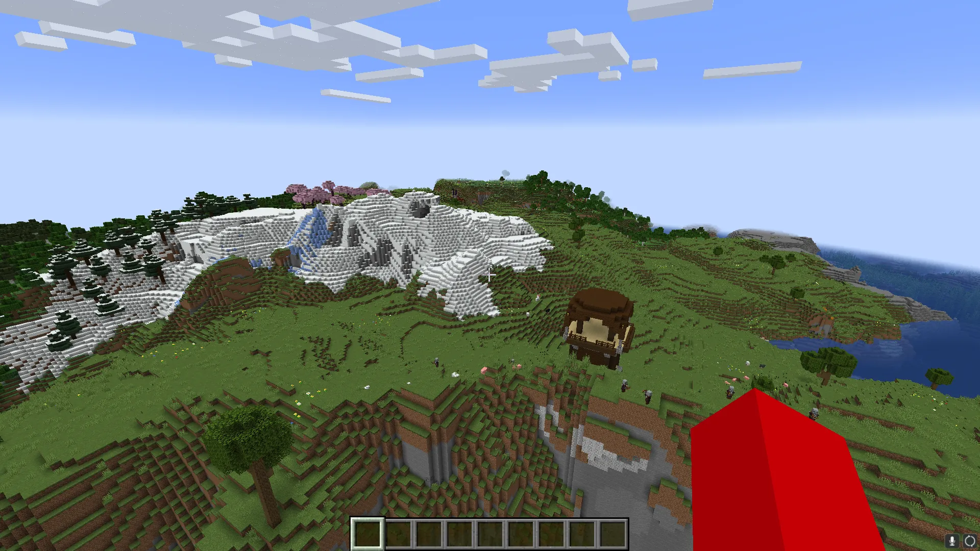 A Minecraft player floating in the air, looking at a Pillager Twoer, a snow biome, some pink Cherry Blossom trees, and a ruined portal.