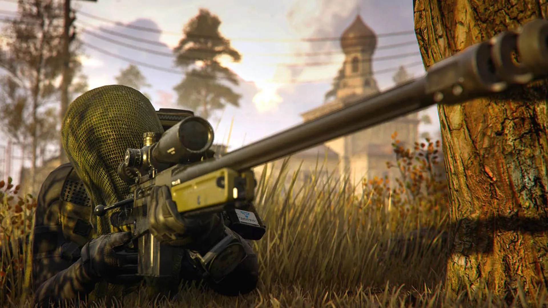 A Sniper wearing a Ghillie Suit lying down in the grass, aiming down a sniper scope.