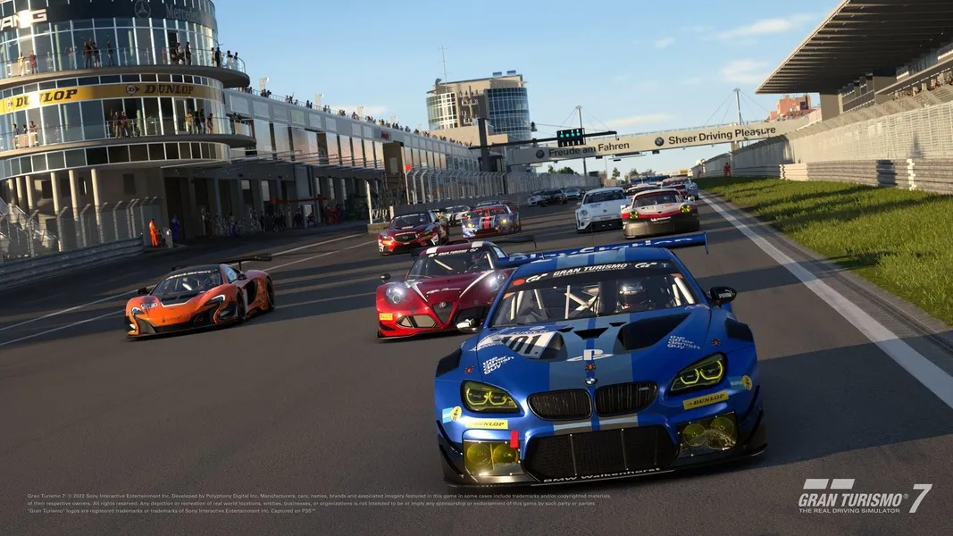 A race at Portimao race track, with cars racing down the finish straight. The lead car is a blue BMW with a PlayStation-themed livery. 