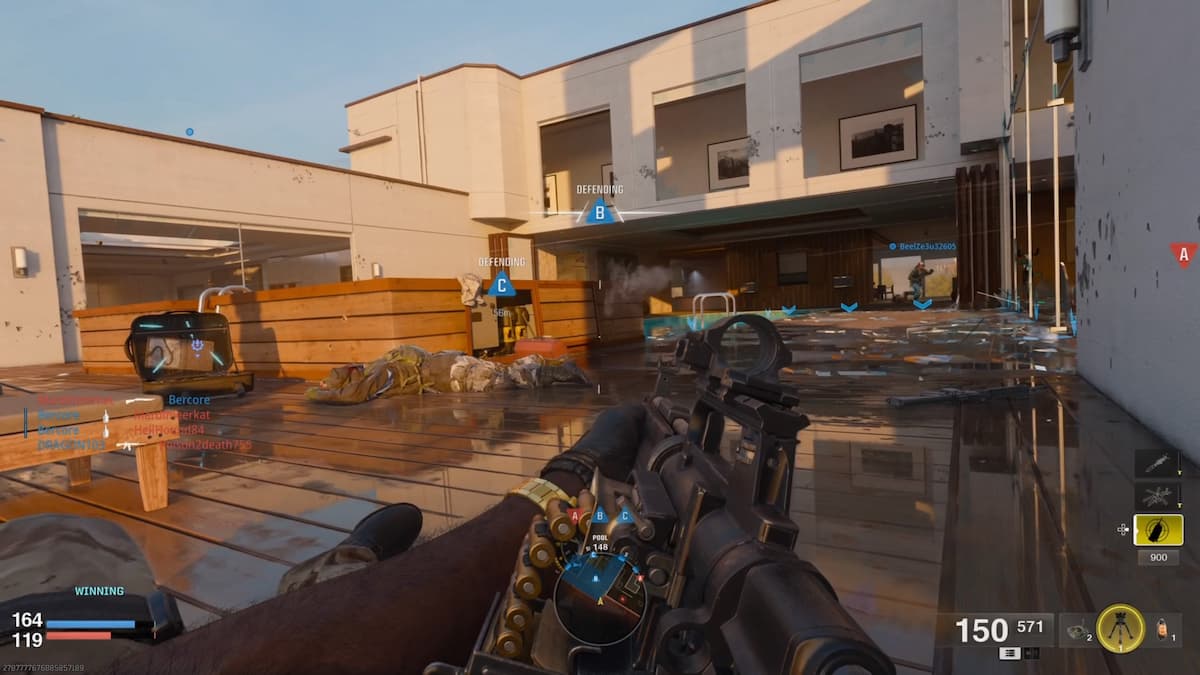 Multiplayer gameplay screenshot from Call of Duty: Black Ops 6 showing a player holding an LMG while lying prone on a wet floor in a Domination match. Teammates and enemies are engaged in a firefight around capture points, with the HUD displaying current objectives and player stats.